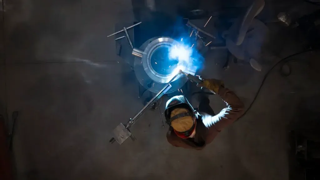 Top down view of a man welding repairing a cylinder